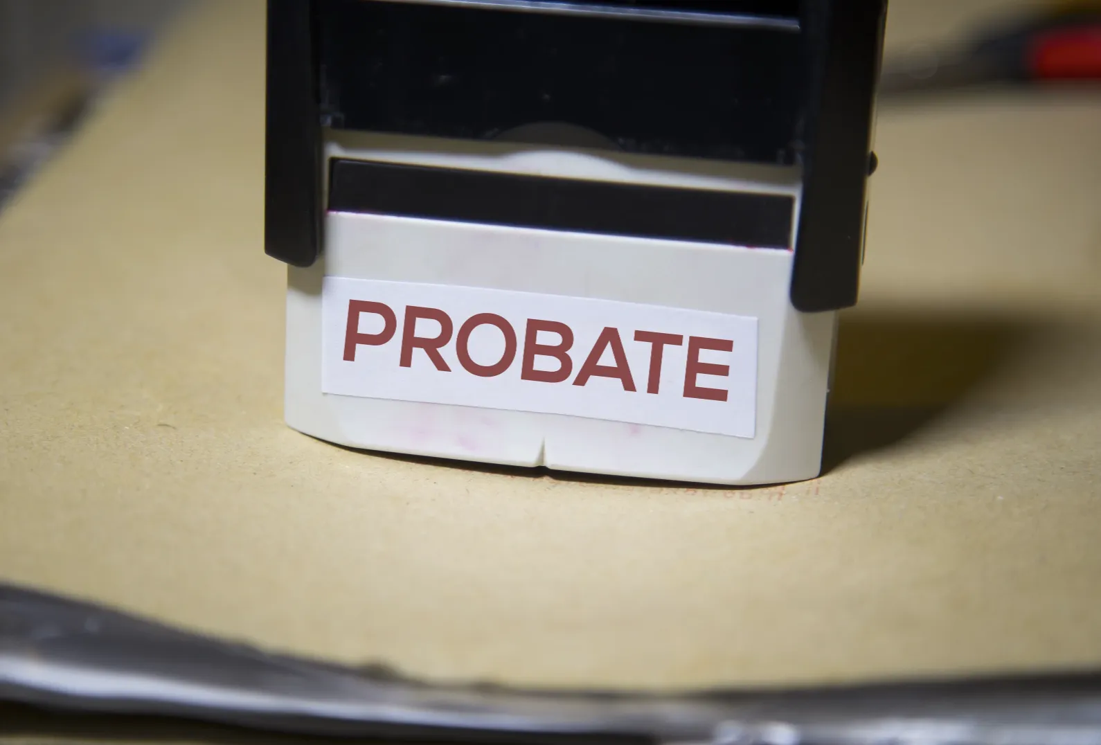 Close-up of a black and white stamp with the red text "PROBATE" on a beige surface.