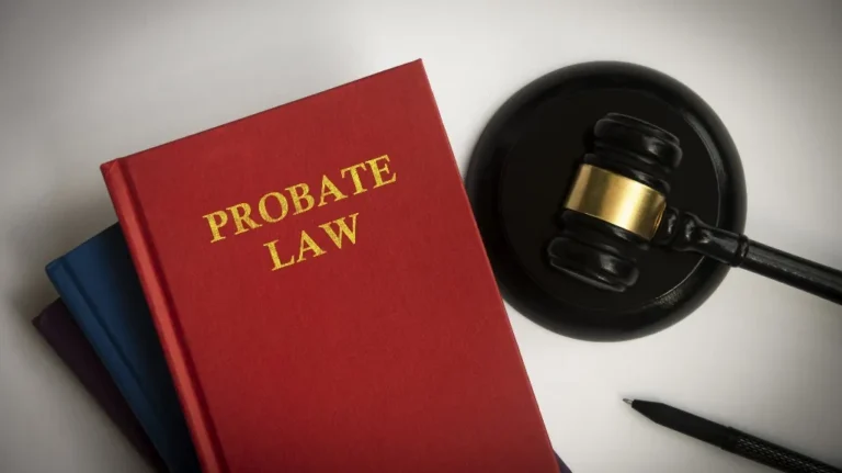 Red hardcover book titled "Probate Law" next to black judge's gavel and pen on white surface.