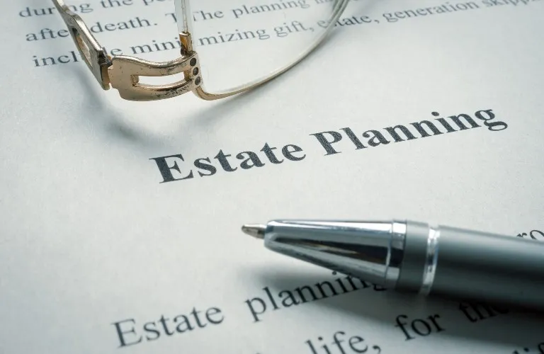 Close-up of a document titled "Estate Planning" with a silver pen and eyeglasses resting on it.