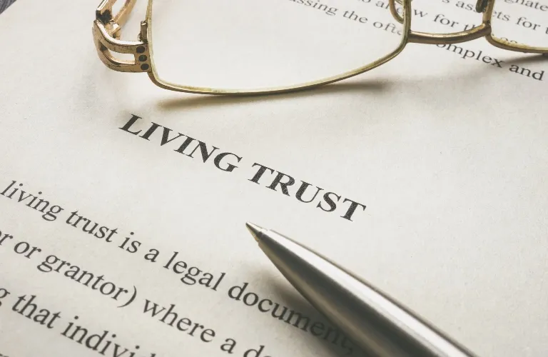 Close-up of a living trust legal document with a pen and eyeglasses on top.